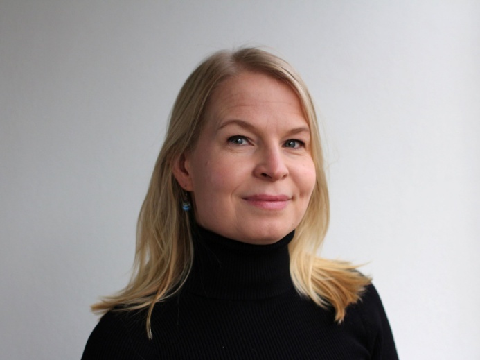 Kuvassa Jotpan projektipäällikkö Milma Arola seisoo harmaata taustaa vasten.